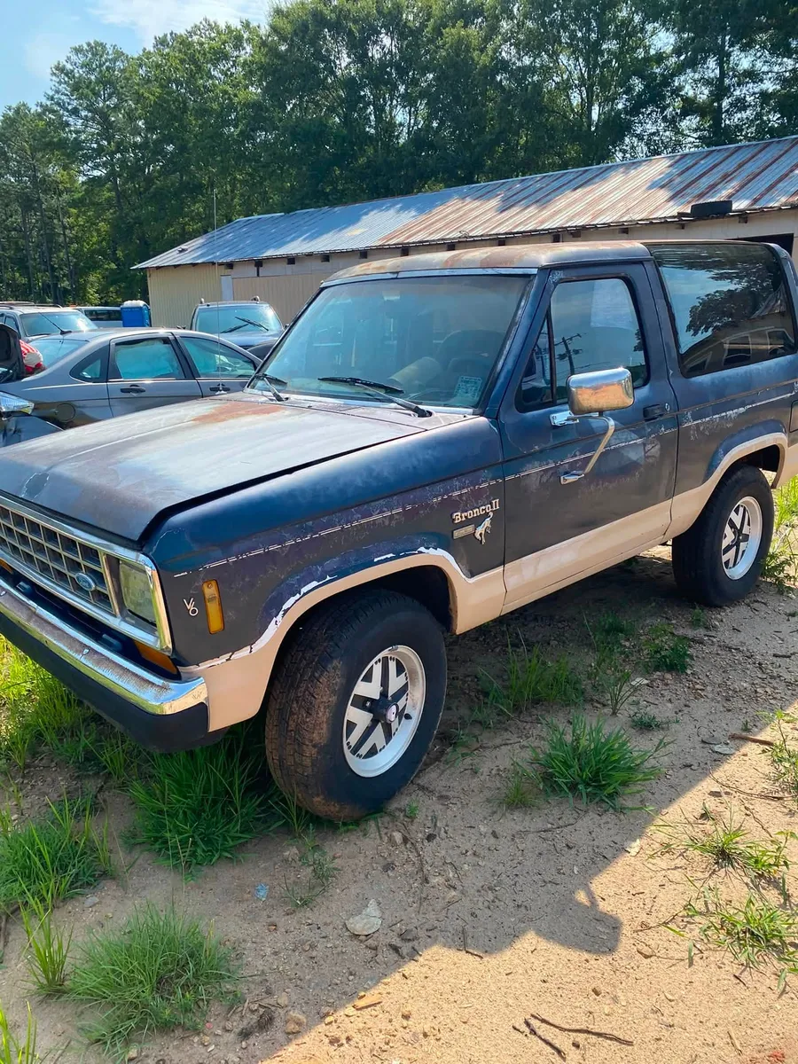 Blue Ford Bronco photographed beside the salvage yard building